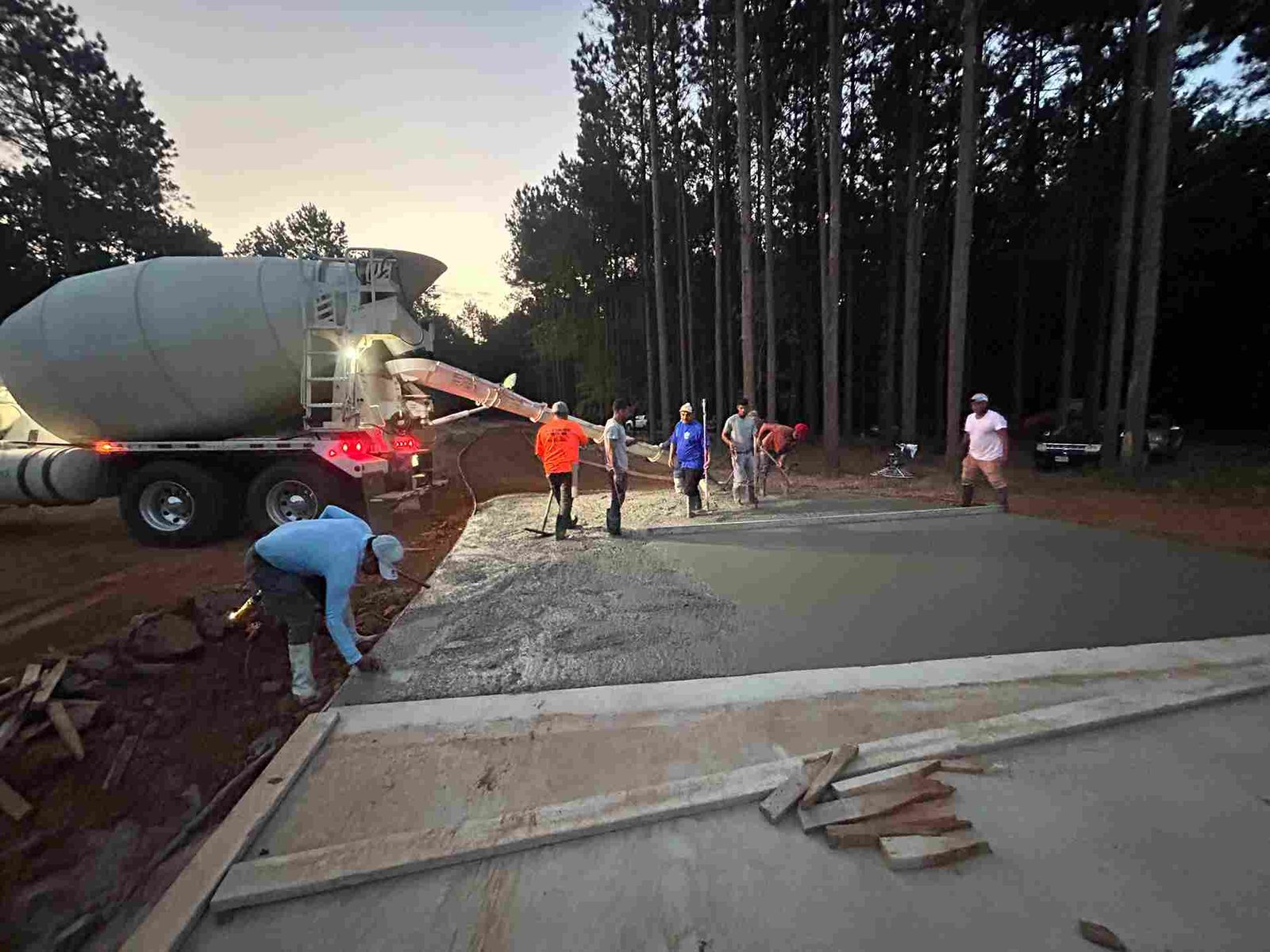 Fred's Concrete Services team pouring a concrete driveway at dusk in East Texas using a ready-mix truck